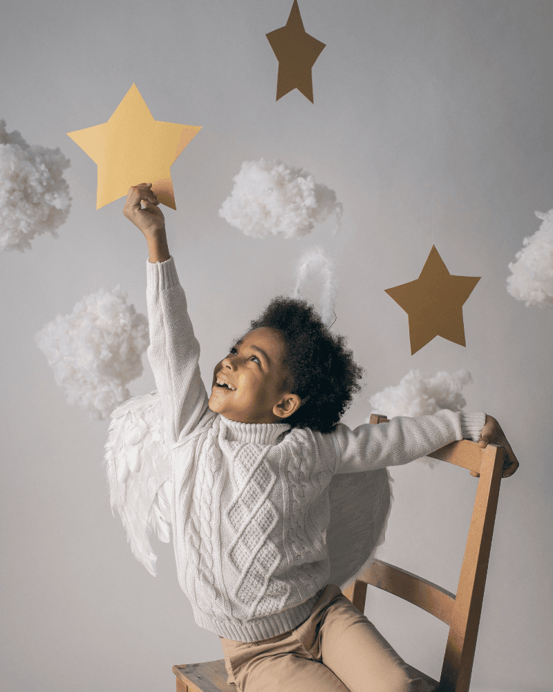 Child reaching for a gold star among clouds