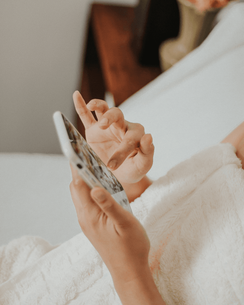 Hands browsing on a phone under a cozy blanket